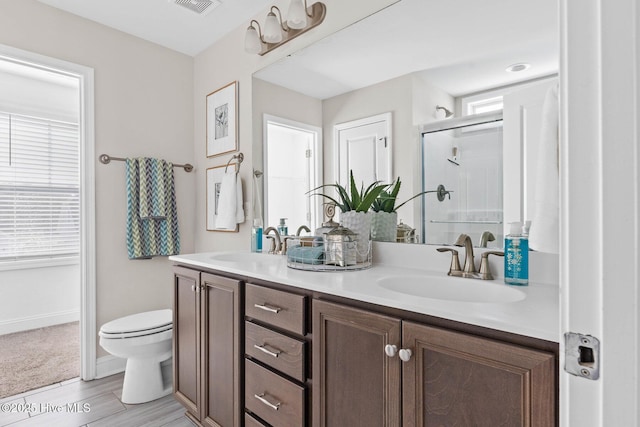 bathroom featuring hardwood / wood-style flooring, vanity, toilet, and a shower with shower door