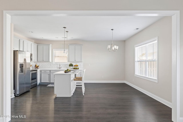 kitchen featuring hanging light fixtures, a kitchen island, a breakfast bar, and appliances with stainless steel finishes