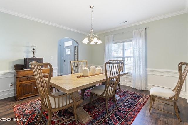 dining space with ornamental molding, a notable chandelier, and dark hardwood / wood-style flooring