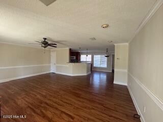 unfurnished living room with dark wood-type flooring, ornamental molding, and baseboards