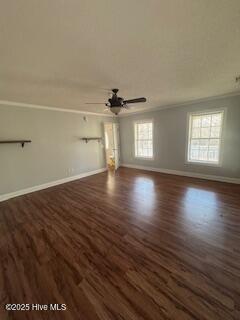 unfurnished living room featuring ornamental molding, ceiling fan, dark wood-type flooring, and baseboards