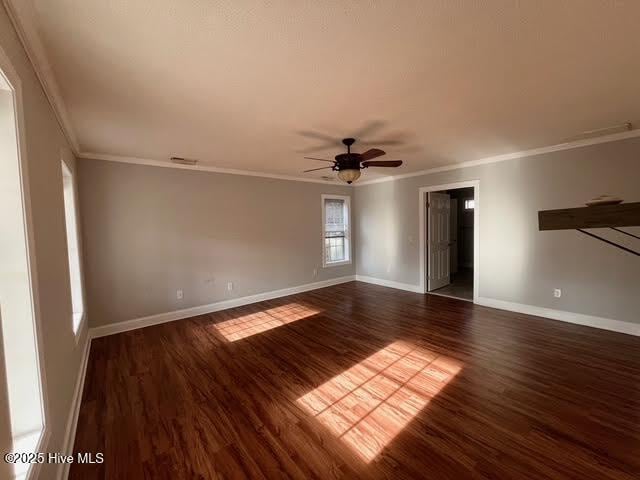 empty room with ceiling fan, baseboards, wood finished floors, and ornamental molding