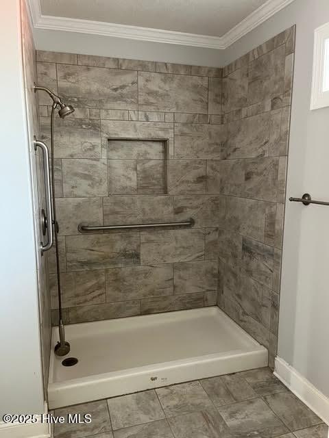 full bath with a stall shower, crown molding, and baseboards