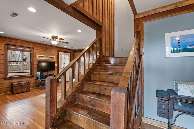 stairs featuring ceiling fan, hardwood / wood-style floors, and wood walls