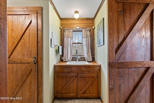 interior space featuring baseboards, ornamental molding, and a sink