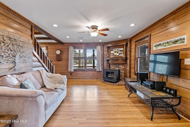 living room featuring wood walls, wood finished floors, stairs, and ceiling fan