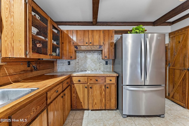 kitchen featuring light countertops, freestanding refrigerator, beam ceiling, and tasteful backsplash