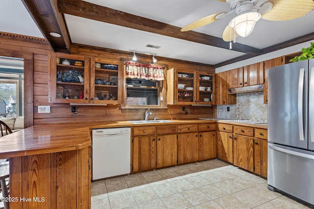 kitchen with beamed ceiling, dishwasher, freestanding refrigerator, and a sink