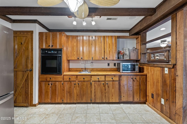 kitchen with stainless steel appliances, sink, light tile patterned floors, and beamed ceiling