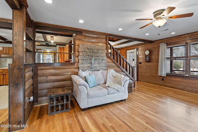 living room featuring log walls, light hardwood / wood-style floors, ceiling fan, and wood walls