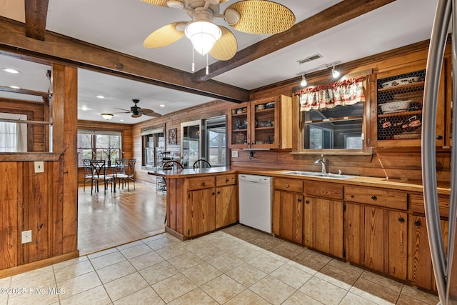 kitchen with wood walls, dishwasher, sink, kitchen peninsula, and beam ceiling