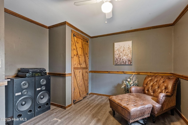 living area featuring ceiling fan, baseboards, ornamental molding, and wood finished floors