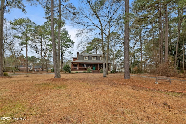 view of front facade with a chimney, roof with shingles, and covered porch