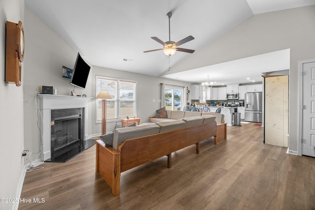 living room featuring wood-type flooring, vaulted ceiling, and ceiling fan with notable chandelier