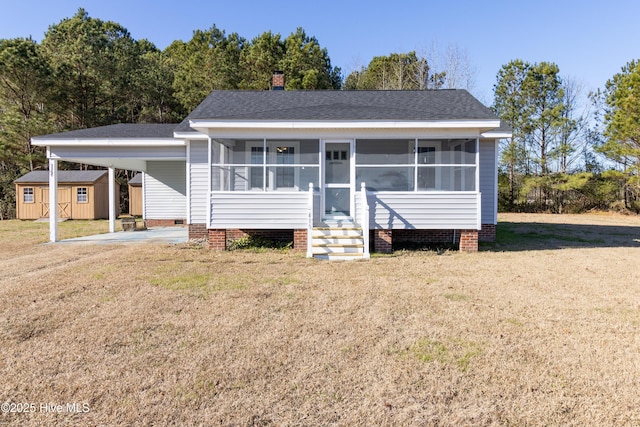 view of front facade featuring a carport, a storage shed, and a front lawn