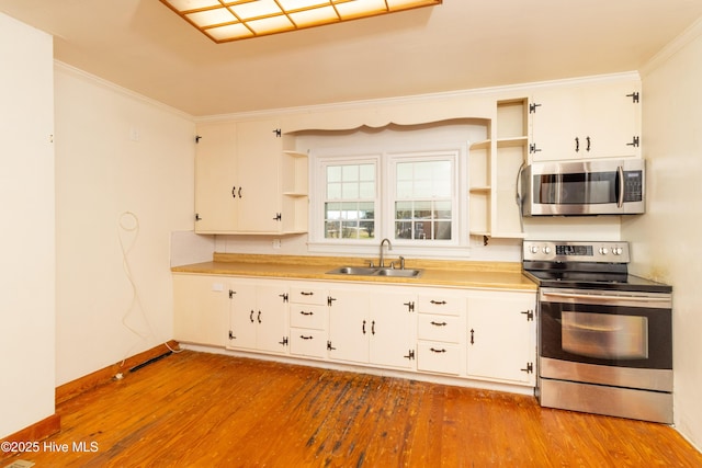 kitchen with appliances with stainless steel finishes, crown molding, sink, white cabinets, and light hardwood / wood-style floors