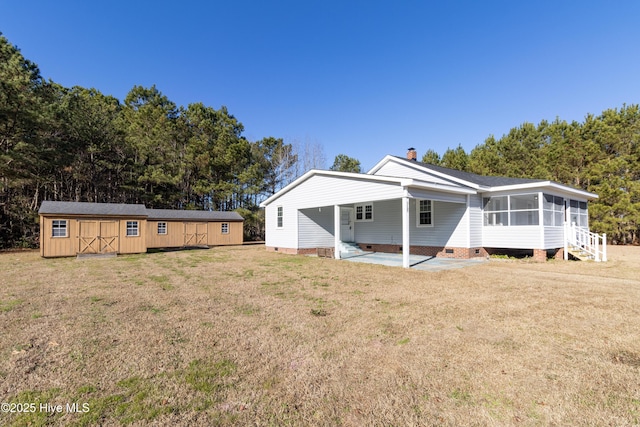 rear view of property with a sunroom, an outdoor structure, and a yard