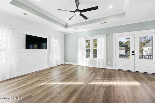 unfurnished living room featuring french doors, wood-type flooring, and a raised ceiling