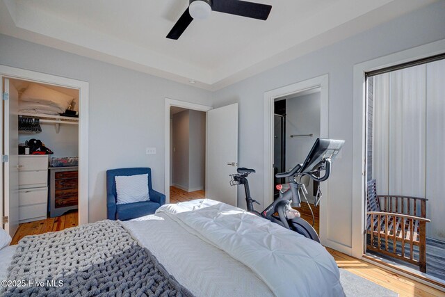 bedroom featuring ensuite bathroom, a tray ceiling, light hardwood / wood-style floors, and a spacious closet