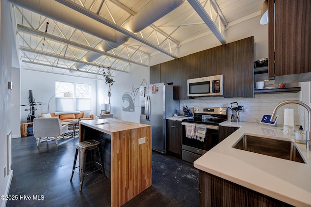 kitchen featuring sink, appliances with stainless steel finishes, tasteful backsplash, a kitchen bar, and wood counters