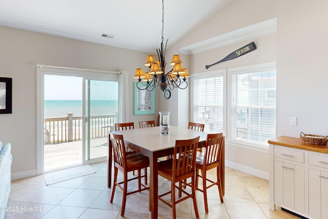 dining space with vaulted ceiling, a water view, light tile patterned flooring, and a chandelier