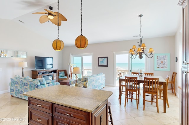 kitchen with ceiling fan with notable chandelier, light tile patterned floors, hanging light fixtures, and vaulted ceiling