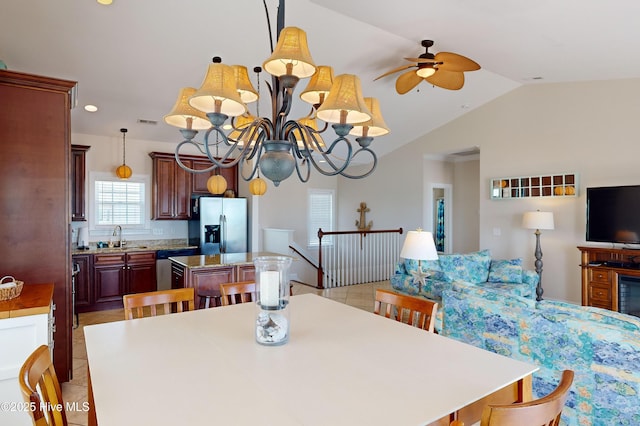 dining space featuring ceiling fan with notable chandelier, sink, light tile patterned flooring, and lofted ceiling