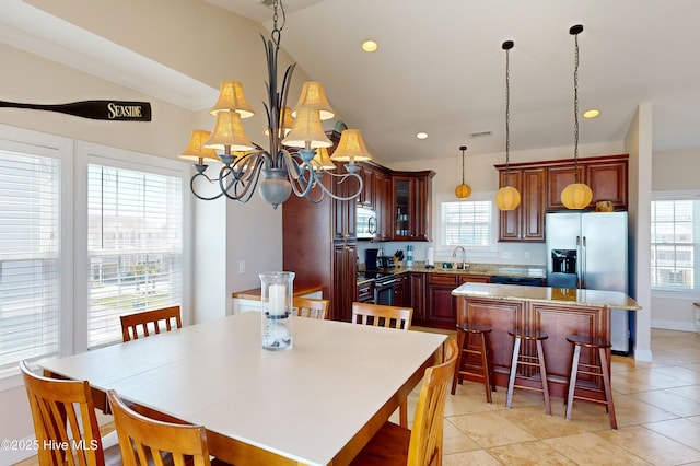 kitchen with a wealth of natural light, a kitchen island, pendant lighting, and an inviting chandelier