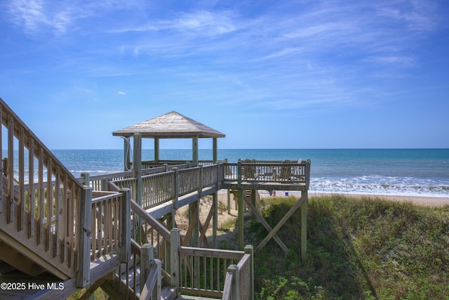 surrounding community with a gazebo, a water view, and a view of the beach