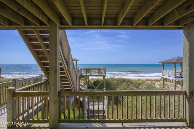 wooden deck featuring a view of the beach and a water view