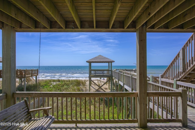 wooden deck with a water view and a view of the beach