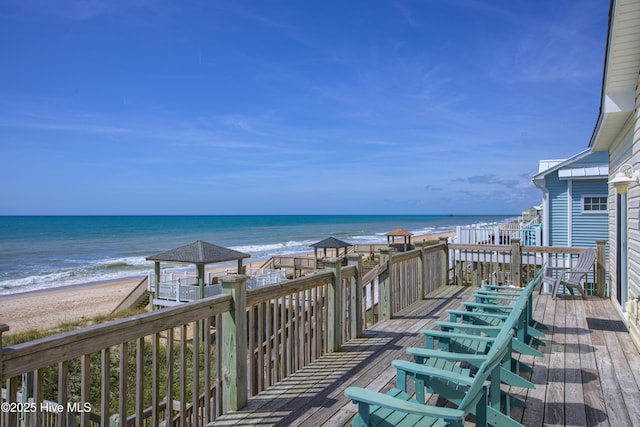 wooden deck with a water view and a beach view