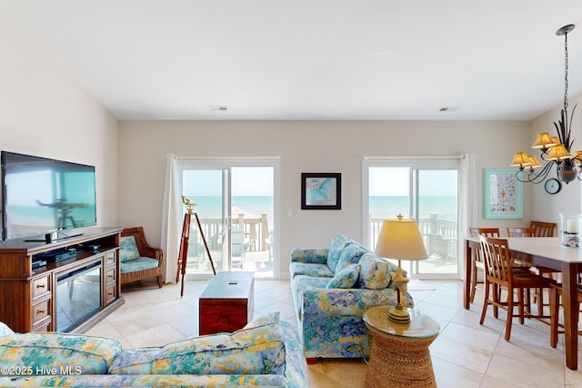 living room featuring a water view, a chandelier, and light tile patterned floors