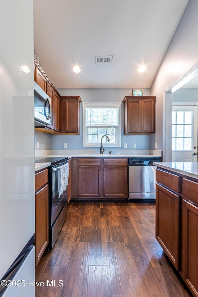 kitchen with a healthy amount of sunlight, appliances with stainless steel finishes, sink, and dark hardwood / wood-style flooring