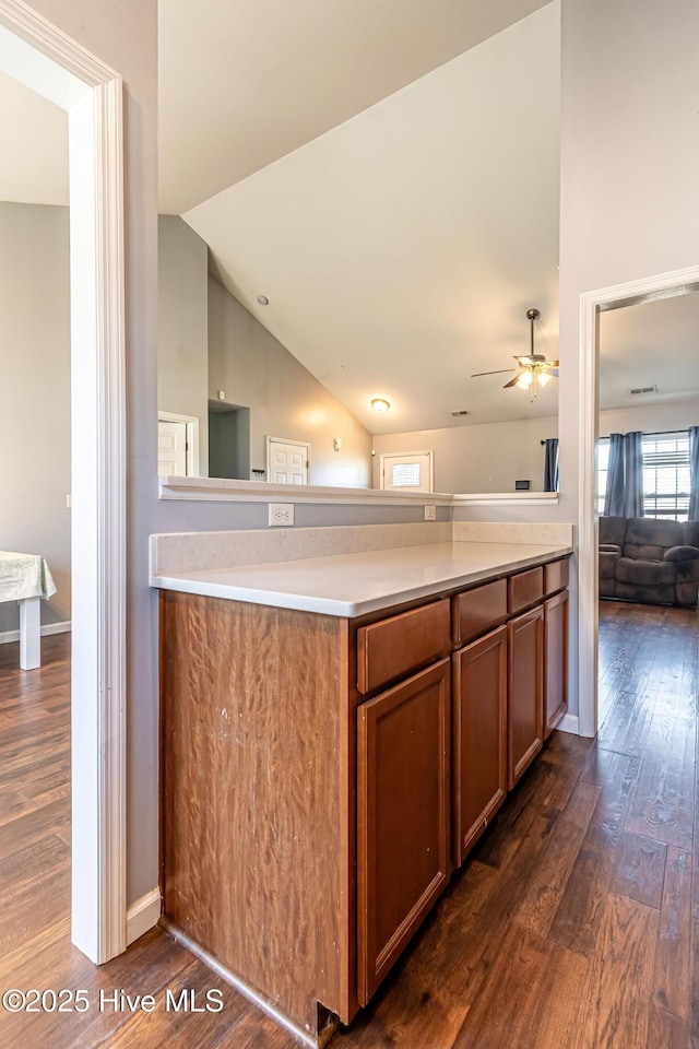 kitchen featuring ceiling fan, lofted ceiling, dark hardwood / wood-style flooring, and kitchen peninsula