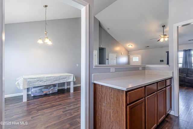 kitchen with pendant lighting, lofted ceiling, dark hardwood / wood-style floors, and ceiling fan with notable chandelier