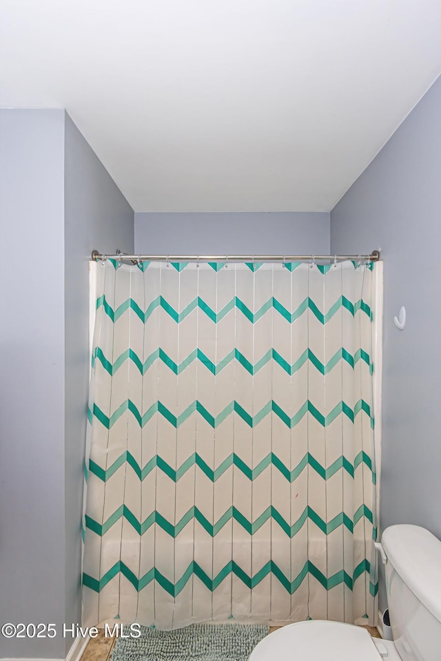 bathroom featuring a shower with curtain and toilet