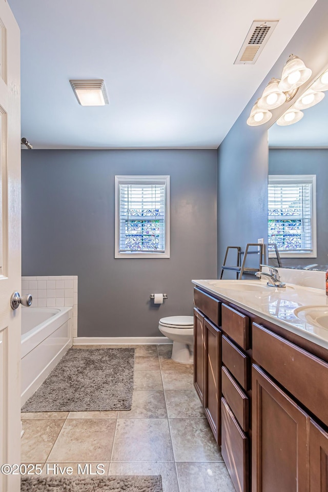 bathroom featuring vanity, a washtub, tile patterned floors, and toilet