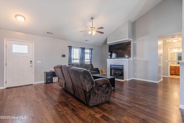 living room featuring ceiling fan, dark hardwood / wood-style floors, a tiled fireplace, and high vaulted ceiling