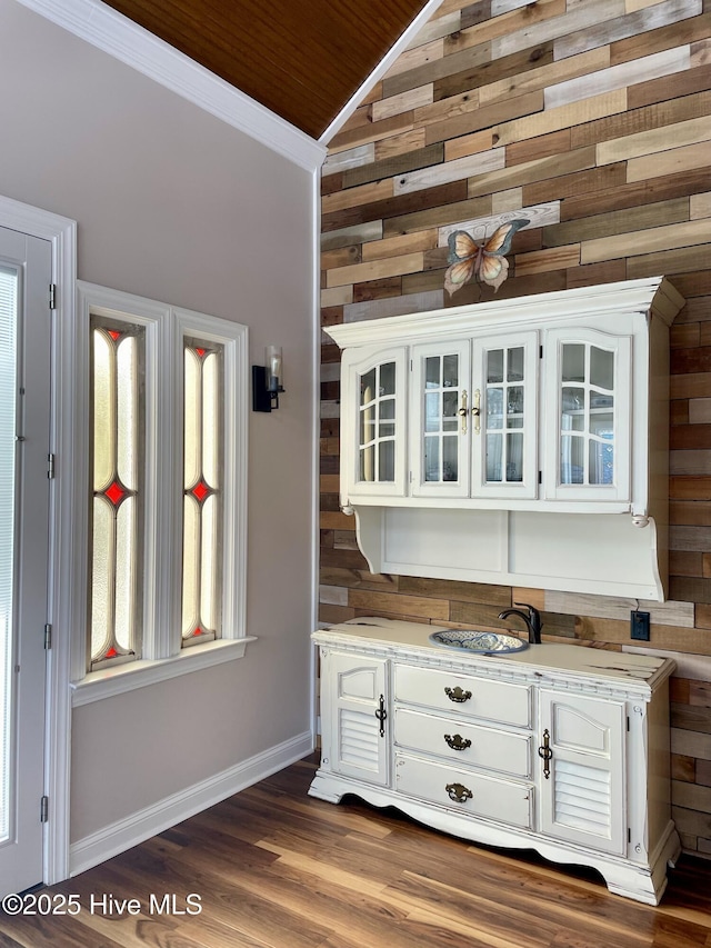 bar with white cabinetry, wooden walls, and lofted ceiling