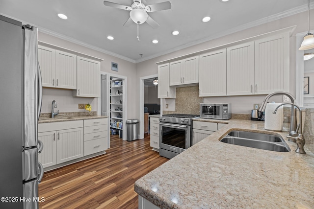 kitchen with hanging light fixtures, white cabinetry, appliances with stainless steel finishes, and sink