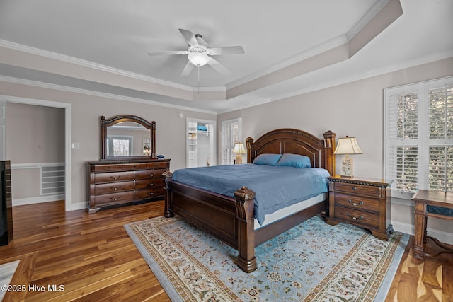 bedroom featuring ceiling fan, ornamental molding, a tray ceiling, and multiple windows