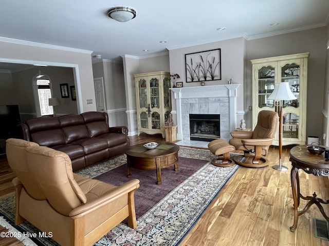 living room featuring a tiled fireplace, hardwood / wood-style flooring, and ornamental molding