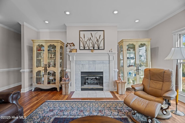 sitting room with hardwood / wood-style flooring, crown molding, a healthy amount of sunlight, and a tile fireplace