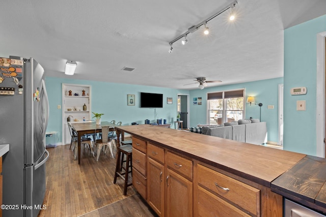 kitchen with a textured ceiling, wooden counters, dark hardwood / wood-style flooring, stainless steel refrigerator, and ceiling fan