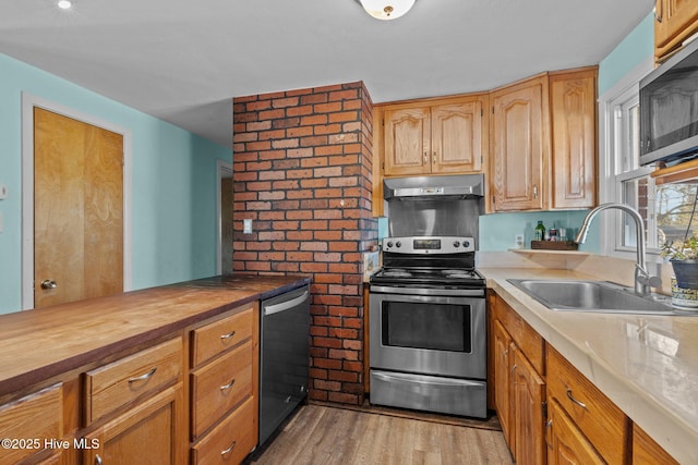 kitchen with butcher block countertops, sink, stainless steel appliances, and light hardwood / wood-style flooring