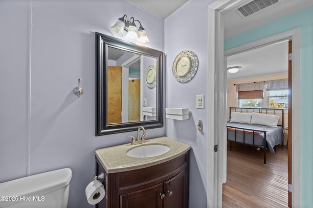 bathroom with hardwood / wood-style flooring, toilet, and vanity