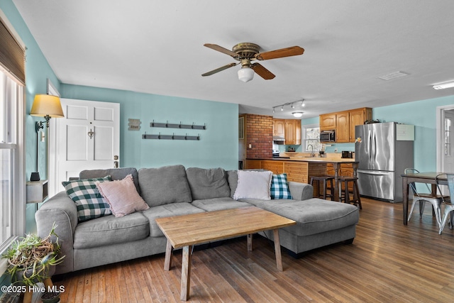 living room with ceiling fan, track lighting, and dark hardwood / wood-style floors