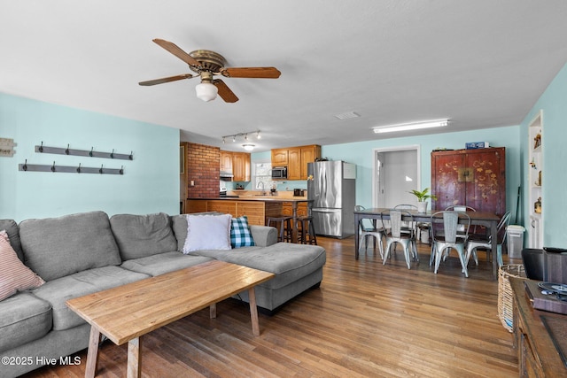 living room with ceiling fan, sink, and light wood-type flooring