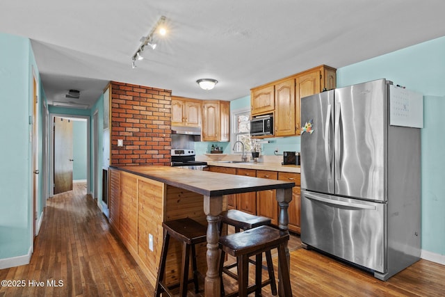 kitchen with a kitchen breakfast bar, stainless steel appliances, hardwood / wood-style floors, and sink